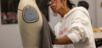 Student working with fabric on body form