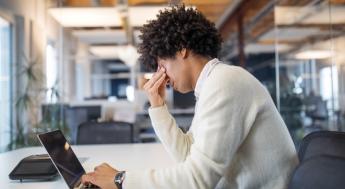 Student at laptop holding head