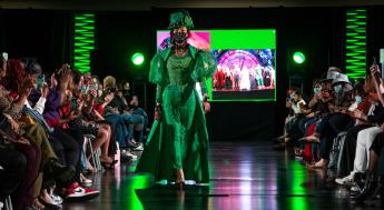 Model walking down runway in emerald green outfit