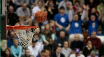 Basketball going into hoop with audience in background