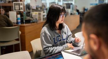 Student wearing UCLA sweatshirt working on laptop