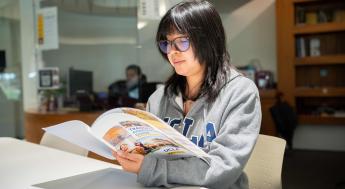 Student wearing a UCLA sweatshirt and browsing a transfer brochure