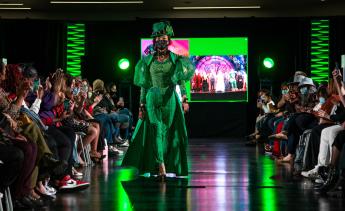 Model walking down runway in emerald green outfit