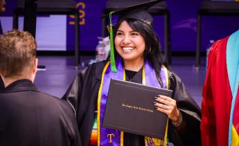 Graduate smiling and holding her diploma