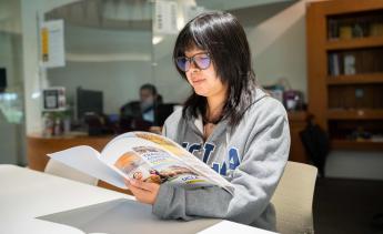 Student wearing a UCLA sweatshirt and browsing a transfer brochure