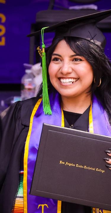 Graduate smiling and holding LATTC diploma 