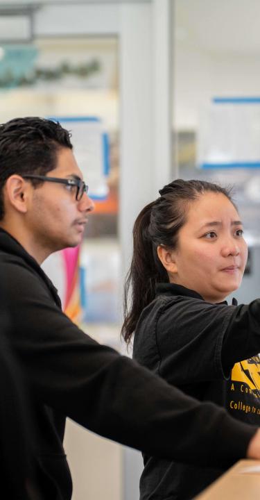 Employee pointing to computer monitor while student looks on