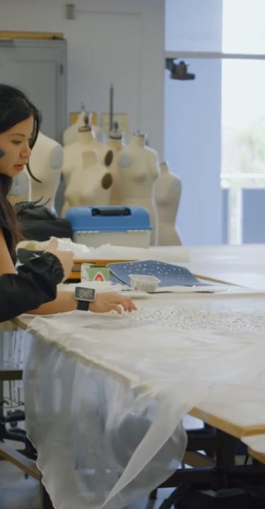 Two students working on designs next to mannequin