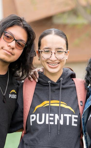 Three Puente students smiling with their arms around each other