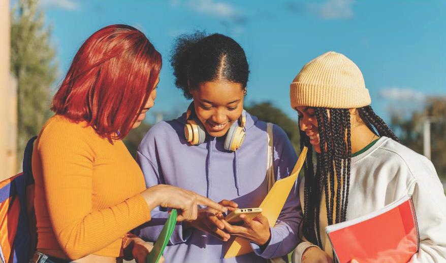 Three students looking at phone together and smiling