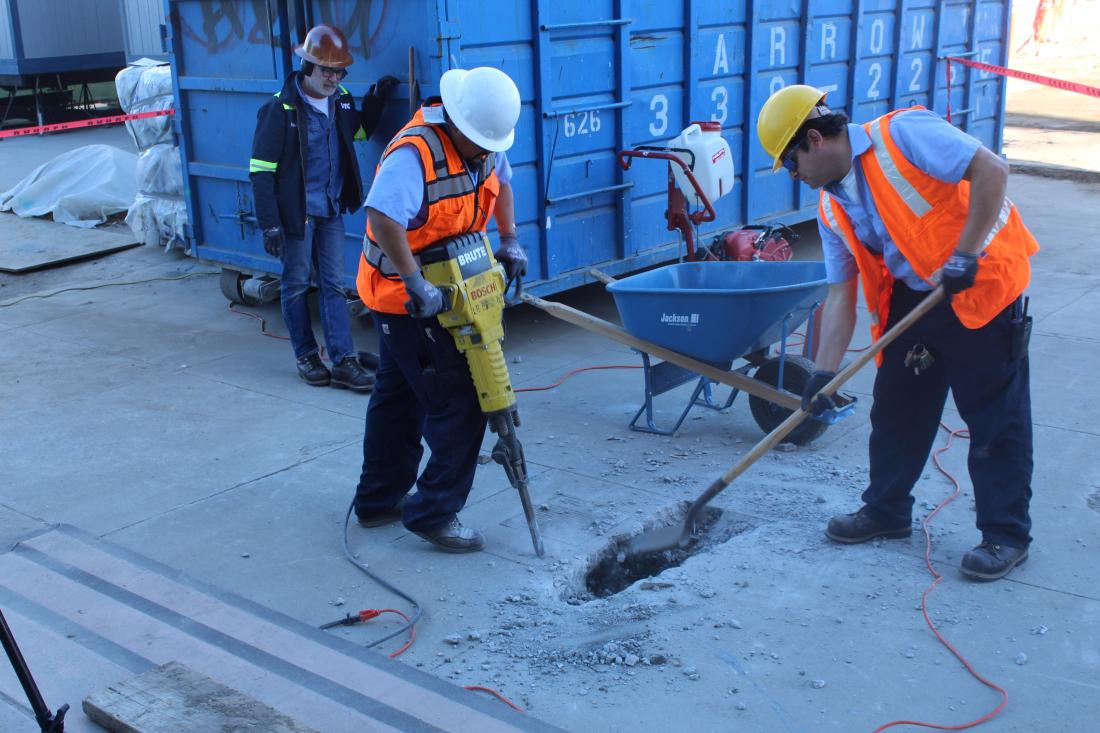 Physical plant workers drilling into concrete with jackhammer