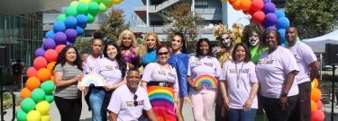 LATTC Pride Club, administrators and drag artists post on stage against rainbow balloons