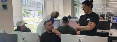Students working at computer station and receiving assistance
