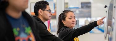Employee pointing to computer monitor while student looks on