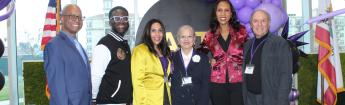 Administrators and alumni smile on stage