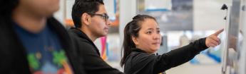 Employee pointing to computer monitor while student looks on